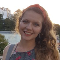 thais+suzane+milessi_esteves.jpg Foto de Thais Suzane Milessi Esteves, uma mulher de pele branca, com cabelos levemente ondulados abaixo dos ombros. Seus olhos são azuis e seus cabelos loiros escuros. Ela usa uma blusinha xadrez de alças finas e algumas flores vermelhas. Possui uma alça de bolsa cinza no ombro direito e tem um lenço vermelho prendendo seus cabelos como uma tiara. Seu rosto está levemente inclinado à esquerda e ela sorri.